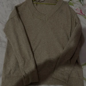 Beige stickad tröja från Vila - Beige stickad tröja från Vila med v-ringad hals och breda ribbade muddar vid ärmslut och nederkant. Perfekt för lager-på-lager och enkel att matcha med jeans eller kjol. Klassisk och stilren design som funkar året runt. Funkar som M 