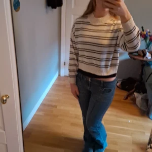 Vit och svart randig stickad tröja - Säljer en mysig stickad tröja i vitt med svarta horisontella ränder. Tröjan har en croppad passform, ribbad hals och muddar vid ärmslut. Perfekt för dig som gillar enkel och stilren design med lite edge. Långärmad och passar till många olika outfits.