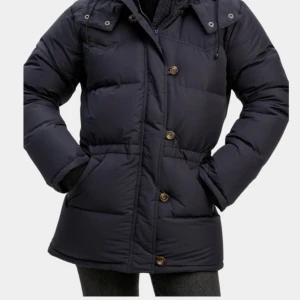 Svart dunjacka från Boomerang i strl small - Svart snygg dunjacka från Boomerang, modell Alexandra Classic Down. Jackan har huva med snörning, knappar och dragkedja framtill samt två stora fickor. Puffig och varm design i klassisk stil, perfekt för kalla dagar. Helt ny, aldrig använd, ingen prislapp dock