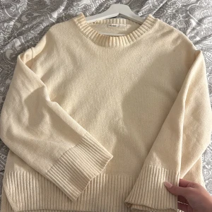 Beige stickad tröja från Pull&bear - Supermysig beige stickad tröja från Pull&bear med breda ribbade muddar vid ärmslut och nederkant. Tröjan har en relaxed fit, rund halsringning och slitsar i sidorna. Perfekt tröja för vardagen.