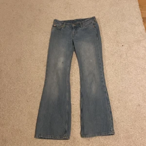 Blå bootcut jeans - Säljer ett par klassiska blå bootcut jeans med normal passform. Jeansen har fem fickor, bälteshällor och dragkedja med knapp. Materialet är slitstarkt denim i bomull och färgen är ljusblå med lätt tvättad look.