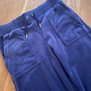 Juicy Couture byxa blå/lila - Fin byxa från Juicy Couture med fickor fram och bak. Knappar på fickorna bak. Dragsko i midjan. Sparsamt använda så i fint skick. Storlek xs. 