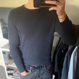 Mörkblå stickad tröja från Riley - Mysig mörkblå stickad tröja från Riley med rund halsringning och långa ärmar. Perfekt för lager-på-lager och enkel att matcha med jeans. Klassisk och stilren modell som funkar året runt.