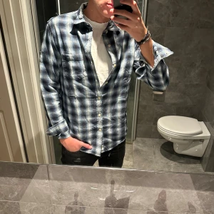 Blå och vit rutig skjorta Ralph lauren denim & supply - Snygg rutig skjorta i blått och vitt från Ralph Lauren denim & supply. Skjortan är i knappt använd och är därför i riktigt bra skick. Jag på bilden är 188cm och bär storlek M. Hör av er vid funderingar;)