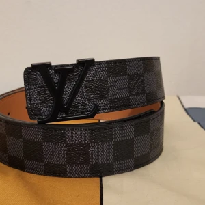 rutigt svart bälte 100 cm - Säljer ett bälte i svart och grått med klassiskt rutigt Damier-mönster. Bältet är gjort i skinn och har en exklusiv känsla, perfekt för att lyfta vilken outfit som helst. Fråga gärna om mer information och kan mötas i upp i Stockholm.
