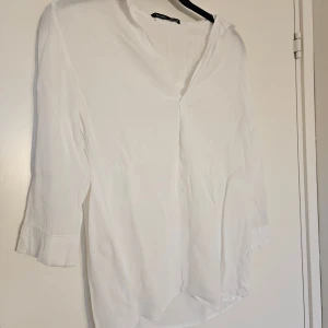 Bershka skjorta  - Vit skjorta från Bershka i tunt och sköntmaterial. Skjortan har v-ringning, trekvartsärmar med manschett och avslappnad passform.