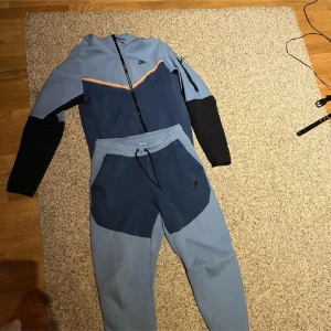 Nike tech blå - Nike hoodie i två nyanser av blått. Köptes för 2300 och är använd typ 2 gånger. Tröjan är i Small och byxorna i Medium.