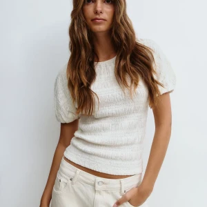 Vit puffärmad blus från Gina Tricot - Supersöt vit blus med puffärmar från Gina Tricot. Toppen har en smockad struktur och är tillverkad i ett lätt och luftigt material. Rund halsringning och kort ärm ger en fräsch och trendig look. Perfekt att styla med jeans eller kjol.