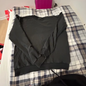 Svart sweatshirt med volang från ONLY - Svart sweatshirt från ONLY med långa ärmar och rund hals. På axlarna finns snygga volangdetaljer och pärlor som ger en extra touch. Tröjan är i mjuk bomullsmix och har ribbade muddar vid ärmslut och nederkant. Perfekt för dig som gillar stilrena plagg med en twist.