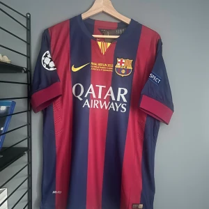 FC Barcelona Neymar Jr 11 matchtröja - Säljer en officiell FC Barcelona fotbollströja från Nike med Neymar Jr och nummer 11 på ryggen. Tröjan har breda blå och röda ränder, Champions League-märke på ärmen och Qatar Airways som sponsor framtill. Tillverkad i lätt och ventilerande Dri-FIT-material. Helt ny med tagg en replika