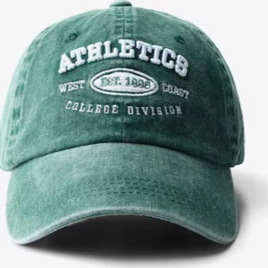 Grön keps från Bershka - Snygg grön keps från Bershka med broderad vit text 'ATHLETICS' och detaljer som 'College Division' framtill 🌸 helt ny med lappen kvar!