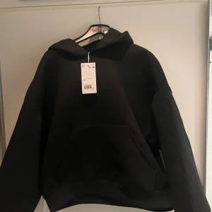 Svart hoodie från Weekday, storlek S - Svart hoodie från Weekday i storlek S. Oversized modell med stor huva och klassisk känguruficka framtill. Tillverkad i mjuk bomullsblandning, perfekt för chill dagar. Enkel och stilren design som funkar till allt.