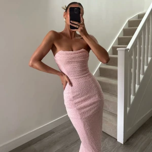 Oh Polly maxi dress ljusrosa - Superfin ljusrosa långklänning med axelbandslös design och figurnära passform. Klänningen har en strukturerad, bubblig yta som ger en unik look. Perfekt för dig som vill sticka ut med en elegant och feminin stil. Endast använd en gång. Oh polly kartongen finns även kvar!