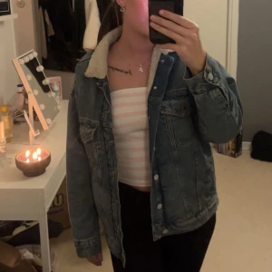 Blå jeansjacka med teddyfoder - Säljer en snygg blå jeansjacka med vit teddykrage och mjukt teddyfoder på insidan. Jackan har klassisk denimlook, knappar framtill och flera fickor. Perfekt jacka inför höst och vinter 😍
