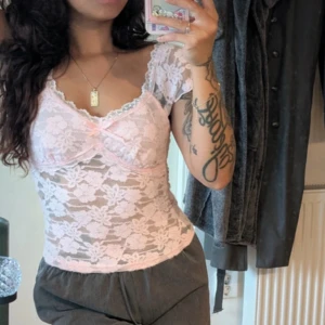 Rosa spetsblus med volangärmar - Söt ljusrosa blus i genomskinlig spets med blommigt mönster. Toppen har v-ringning, liten rosett framtill och volangdetaljer vid ärmarna. Figurnära passform och korta ärmar ger en romantisk vibe. Nypris 450kr💕