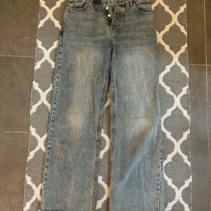 Blå raka jeans från Zara, strl 36 - Snygga blå jeans från Zara i rak modell med klassisk femficksdesign och knappgylf. Jeansen har en ljus tvätt och är tillverkade i bomull. Perfekta för en avslappnad och trendig look.