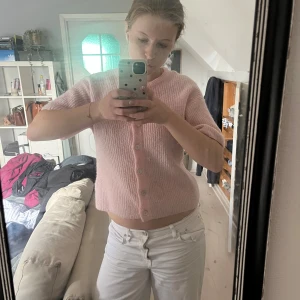 Ljusrosa stickad blus med knappar - Superfin ljusrosa stickad blus med korta ärmar och rund hals. Blusen har en croppad passform och stängs med pärlemorknappar framtill. Perfekt för dig som gillar en söt och enkel stil. Köpt på Gina för 300, säljes för 200. Använd enstaka gånger 💞