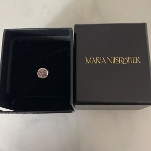 Silverörhänge Skull Maria Nilsdotter - Coolt örhänge i silver från Maria Nilsdotter med en rund platta och graverat döskalleansikte. Perfekt för dig som gillar detaljer och vill sticka ut med din stil.Levereras i original ask.kvitto finns och påsen 