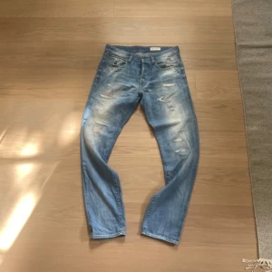 Blå slitna jeans från G-Star RAW - Säljer ett par ljusblå jeans från G-Star RAW med slitningar och distressed detaljer både fram och bak. Jeansen har straight passform.