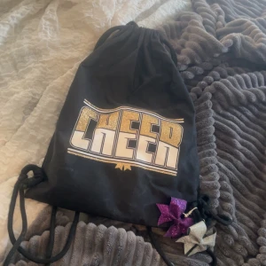 Cheerleading gympapåse - Säljer min gamla cheer gympa påse med två små glittriga rosetter Lila och grå