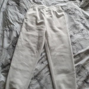 Vita mjukisbyxor med resårmidja - Säljer ett par vita mjukisbyxor med elastisk midja och raka ben. Byxorna är tillverkade i mjukt material som känns skönt mot huden. Perfekta för chill dagar eller när du vill vara extra bekväm. Passar dig som gillar enkel och clean stil.