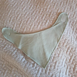 Dregglis / haklapp - Ljusgrön dregglis/haklapp i mjuk fleece med praktisk kardborreknäppning. Triangelformad design som sitter snyggt runt halsen och är enkel att ta på och av. Aldrig använd!