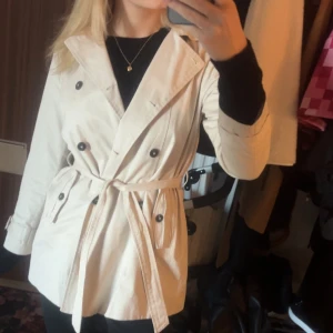 Intresse koll beige kappa  - Intresse koll beige kappa med knappar och riktiga fickor på båda sidor och ett skärp 