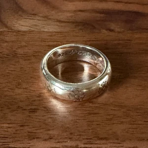 Silverring med ingraverade blommor - Säljer en fet silverring från Chrome Hearts med snyggt, detaljerat mönster runt hela ringen. Insidan är graverad med märkets logga och årtal. Perfekt accessoar för dig som gillar statement-smycken och exklusiv streetstyle. Size 10.  Stainless steel