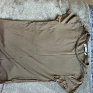 Beige t-shirt från 157 - En basic beige t-shirt från 157 med rund halsringning och korta ärmar. Tillverkad i mjuk bomull, perfekt för en clean och avslappnad stil. Enkel att matcha med jeans eller shorts.