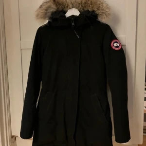 Svart parkas från Canada Goose  - Svart parkasjacka från Canada Goose. Modell: Victoria. Bra skick. Köpt på NK Stockholm. Har inget kvitto därav priset. 