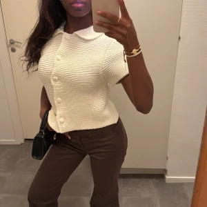 Stickad kofta med krage och knappar - Vit stickad kofta med korta ärmar, krage och stora knappar framtill. Koftan är ribbad och har en croppad passform som ger en fräsch och modern look 🎀❄️