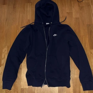 Mörkblå Nike hoodie med dragkedja - Helt splitterny Nike zip-up hoodie. Har används ett fåtal gånger. Inga defekter alls. Säljer för den va för stor för mig, jag är pinnsmal. Väldigt bra pris här också. Skulle säga att passformen är typ mellan small och medium. Möts gärna upp i Stockholm men går även att skicka. Kontakta vid frågor