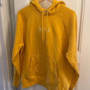 Gul hoodie från Polar Skate Co - Gul hoodie från Polar Skate Co med broderad logga på bröstet. Klassisk känguruficka, snörning i huvan och mjuk insida. Perfekt för dig som gillar streetwear och vill sticka ut med en färgglad look.