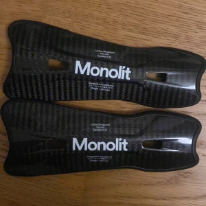 Monolit benskydd i kolfiber - Säljer ett par svarta benskydd från Monolit, tillverkade i lätt kolfiber och designade i Skandinavien. De har ett snyggt kolfibermönster, är ergonomiskt formade och väger bara ca 40 gram. Perfekt för dig som vill ha smidigt och stilrent skydd på planen. Nypris 800 så säljer för hälften och de är som nya. 