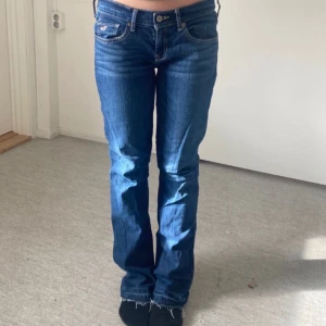 Holliester blå bootcut jeans -  Snygga blå Hollister-jeans med bootcut och låg midja. Klassisk femficksmodell med kontrastsömmar på bakfickorna. Jeansens uppsprättningar syns på bilderna. Passform: W27 L35, men de är små i storleken, så de passar nog bäst om du brukar ha 34–36. Pris går att diskutera, och hör gärna av dig om du har några frågor!