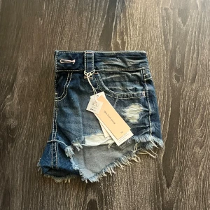 Lågmidjade jeansshorts med slitningar - Säljer mina helt nya mörkblå denimshorts med låg midja från gina tricot 14+ då dom är förstora och därför inte kommit till någon användning. Dom har även kvar sina båda lappar och de har detaljer på fickorna, en fransig kant och slitna detaljer. Nypris 299 därför priset nu men de kan såklart diskuteras❣️
