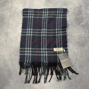Burberry Halsduk - Skick: 7/10 (Vintage), begagnad, inga defekter. | Vad som ingår: Endast halsduken. | Ordinarie pris: +- 4000 SEK / 400 €. | ​​OBS: Halsdukarna finns i samma färgsättning men kan skilja sig något i modell eller detaljer, beroende på tillverkningsår eller kollektion
