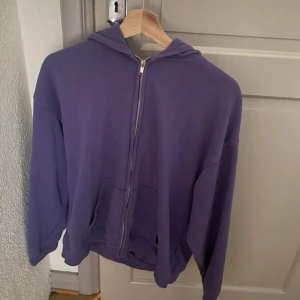 Lila hoodie med dragkedja - Säljer en lila hoodie med hel dragkedja och huva. Tröjan har två fickor framtill och är långärmad med ribbade muddar. Perfekt för chill dagar och enkel att matcha med jeans eller mjukisbyxor.