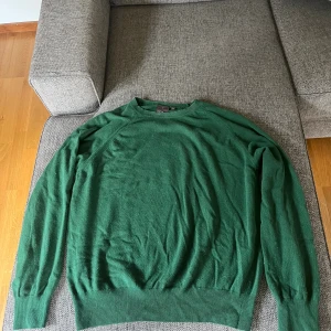 Grön stickad tröja Oscar Jacobson S - Tröjan är i merion ull och är tyvärr tvättad varmt en gång och har därför blivit större så på tagen så står det small men den är vad jag skulle säga large eller XL. Annars är den i toppen skick förutom en liten fläck i kragen. Fråga bara om ni undrar nått eller vill ha fler bilder.