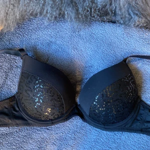 Svart paljett-bh från Bodyzone KappAhl - Snygg svart pushup bh från Bodyzone by KappAhl i storlek B70. Kuporna är dekorerade med svarta paljetter. Axelbanden är justerbara. 