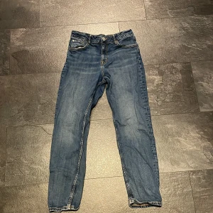 Blå tapered jeans från H&M, stl 16 - Snygga blå jeans från H&M med relaxed fit och justerbar midja. Modellen har tapered ben och klassiska fem fickor. Jeansen är tillverkade i bomull och har kontrastsömmar för en cool look. Perfekta för dig som gillar avslappnad stil.