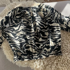 Blus från H&M - Säljer en svartvit blus från H&M i storlek M, men sitter som en S. Blusen har långa ärmar med resår vid ärmslut och midja, vilket ger en snygg puffig effekt. Materialet är lätt och känns skönt mot huden. Använd en gång!