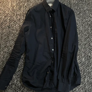 Acne Studios skjorta - Klassisk svart skjorta från Acne Studios i bomull med normal passform. Skjortan har knappar framtill, lång ärm och stilren krage. Perfekt för dig som gillar minimalistisk och clean stil.