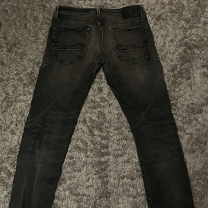 Jack & Jones Glenn 32/32 - Svarta slim fit jeans från Glenn i storlek 32/32. Snygg tvätt med lätt slitning och klassiska fem fickor. Jeansen har smal passform och är tillverkade i stretchigt denim för skön känsla. Perfekta för dig som gillar en modern och stilren look.