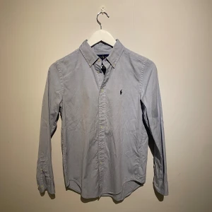 Ljusblå skjorta från Ralph Lauren - Klassisk ljusblå skjorta från Ralph Lauren med button-down krage och broderad logga på bröstet i bomull. Skjortan är i barnstorlek 16 år! Kan bäras som en XS i vanlig storlek! 