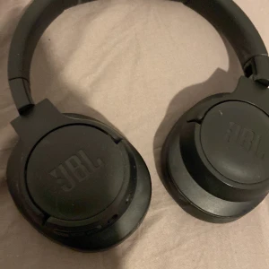 JBL Over-Ear Wireless Headphones - Snygga svarta JBL over-ear hörlurar med trådlös funktion. Mjuka öronkuddar och tydlig L/R-markering för komfort. Fällbar design för enkel transport. Mindre yttre slitage syns, men i gott skick och fullt fungerande. Använda 1-2 gånger ligger bara och skräpar 