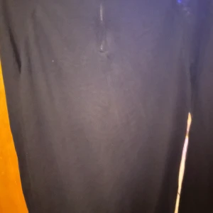 Svart merinoulltröja Dressmann L - Svart långärmad tröja från Dressmann i mjuk merinoull. Tröjan har en hög krage med half zip och ribbade muddar vid ärmslut och nederkant. Perfekt för dig som gillar stilren och enkel design med lite sportig touch.