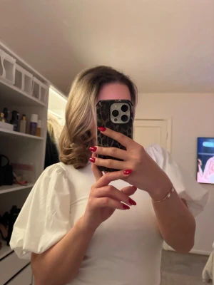 Vit topp med puffärm och öppen rygg - Säljer en vit croppad topp med stora puffärmar och öppen rygg. Toppen har en stilren och modern look med rund hals och är tillverkad i ett mjukt, slätt material. Perfekt för dig som vill sticka ut med coola detaljer och volym på ärmarna.