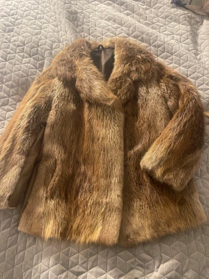 Brun pälsjacka från Päls Bruno - Snygg vintage pälsjacka från Päls Bruno i olika bruna nyanser. Jackan har klassisk rak passform, lång ärm och mjukt foder. Pälsen är tät och fluffig, perfekt för kalla dagar. Märke broderat på insidan. Riktigt statement-plagg för dig som vill sticka ut.
