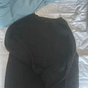 Mörkgrå stickad tröja Vero Moda - Mysig mörkgrå stickad tröja från Vero Moda i storlek M. Tröjan har en enkel rund halsringning och långa ärmar, perfekt för att hålla dig varm under kyliga dagar. Passar dig som gillar en klassisk och stilren look.